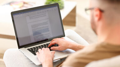 Man working with document online while sitting on sofa as MLA Format Examples